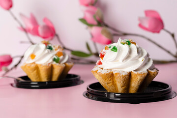 Small delicious pastries decorated with a sakura branch. Isolated on pink background.