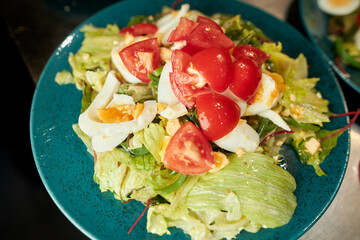 salad with vegetables and boiled eggs on a ceramic plate, close-up. salad of vegetables, herbs, tomatoes and boiled eggs on a plate