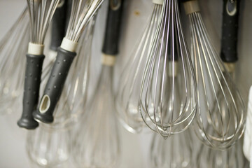 Wire whisk stainless steel hanging on the bar. whisks hang on a magnetic panel on the wall in the...