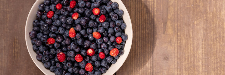 Strawberries and blueberries in bowl on a rustic wooden table. These super-food berries are part of a healthy diet promoting a healthy heart and well being.Big Pile of Fresh Berries
