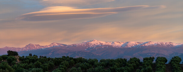 Spectacular lenticular clouds over the snowy peaks of the Sierra Nevada (Granada, Spain) at sunset