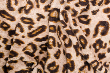 Wavy fabric with the reflection of the skin of wild animals - leopard, cheetah, hyena. Print on leopard skin fabric, close up