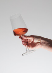 A hand holding a glass with rose wine
