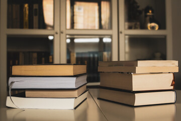 A close-up of two stacks of books against a blurred interior background