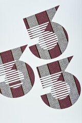 three number three scrapbook paper with stripes shapes on a relatively light surface 