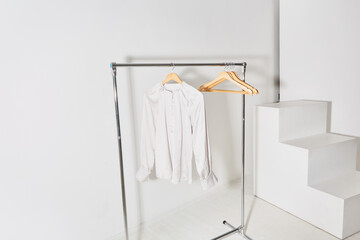 spacious bright studio with a mobile clothes hanger. a clothes rail with a beige shirt hanging,...