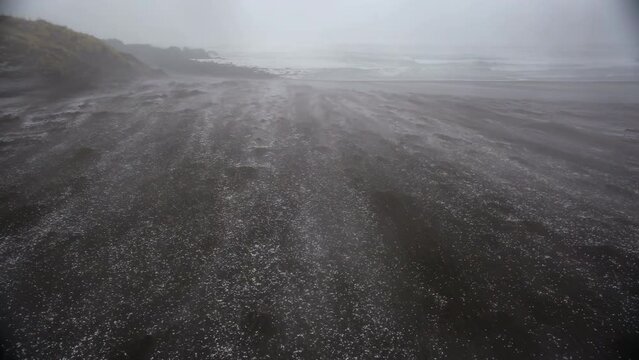 snow carried by wind swirling accross a sandy beach, Sandvik, Iceland