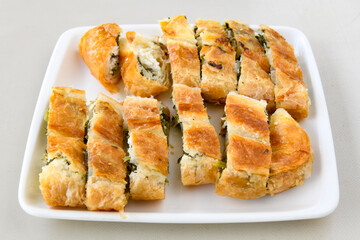 Turkish style meat stuffed filo dough borek served kol boregi. Cheese and minced pie are sliced on a marble background. Turkish name: Kol Boregi, ispanakli, kiymali, Su Boregi