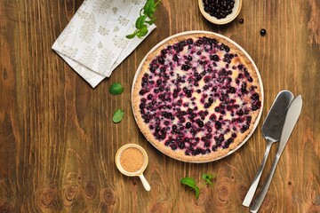 Shortcrust pastry tart with black сurrant and sour cream filling on a ceramic plate on a wooden background. Rustic style. blackcurrant recipes