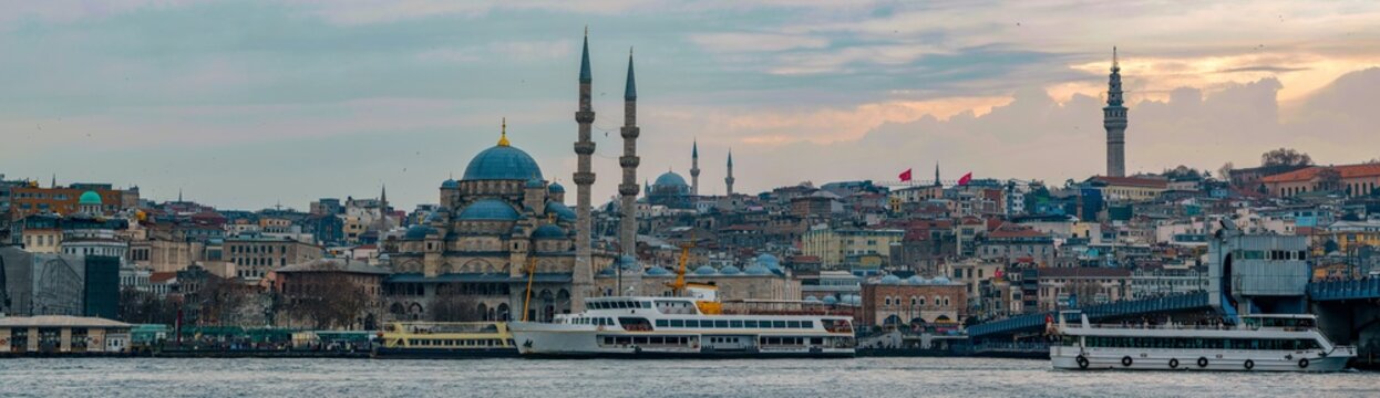 New Mosque Ottoman imperial mosque located in the Eminönü quarter of Istanbul, Turkey. Strait of Bosporus with ships in foreground and sunset in background. Turkey 2023