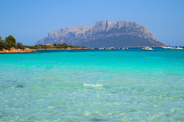 Porto Istana, Sardinia - August 8, 2019 : Shalow azure waters of the Mediterranean Sea on the popular beach of Porto Istana facing the island of Tavolara in Sardinia, Italy