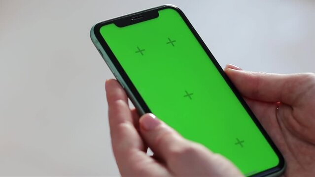 Girl scrolling phone green screen browsing social media chroma key reading news close up hands