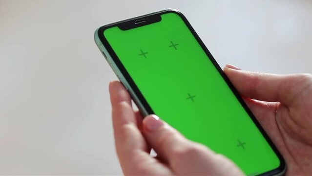 Girl scrolling phone green screen browsing social media chroma key reading news close up hands