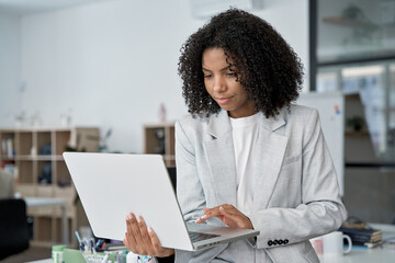 Middle age business woman working, browsing, and typing on touchscreen pc laptop. African American...