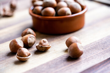 Hazelnuts in a shell and nutshells in ceramic bowl on rustic cutting board
