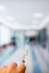 Vertical view of hand holding a syringe in the room of a hospital with copy space