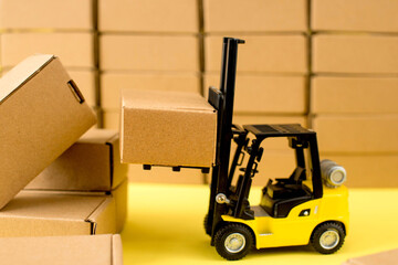Forklift truck raises cardboard boxes on a yellow background. Cargo sorting concept