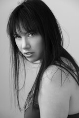 Black and white portrait of a beautiful caucasian woman in her 30s. She has long black hair with bangs. 