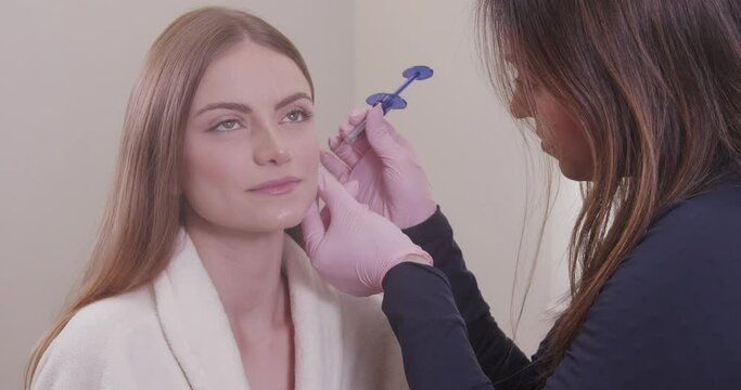 Woman wearing bathrobe in beauty clinic, aesthetics, patient, cosmetic procedures. application of hyaluronic acid. on the lips.