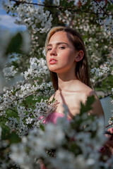 A young girl in a blooming garden. Flowering trees, travel, seasonal April background.