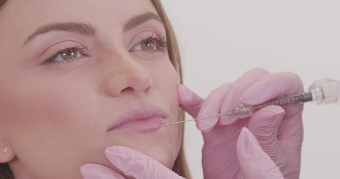 Woman wearing bathrobe in beauty clinic, aesthetics, patient, cosmetic procedures. application of hyaluronic acid. on the lips.