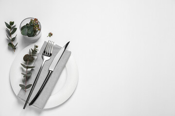 Stylish setting with cutlery and eucalyptus leaves on white background, top view. Space for text