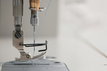 Modern sewing machine on blurred background, closeup. Space for text