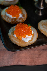 Tasty appetizer for dinner, small pancakes bliny with red fish caviar and sour cream