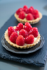 Artisanal baked small tart with cream and fresh ripe red raspberry