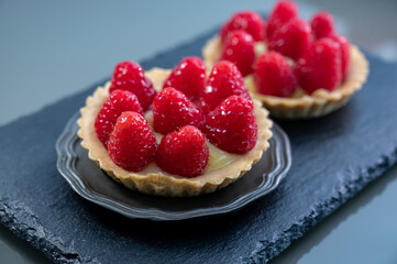 Artisanal baked small tart with cream and fresh ripe red raspberry