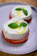 Sliced white ball of Italian soft cheese Mozzarella di Bufala Campana served with fresh green basil and red tomato