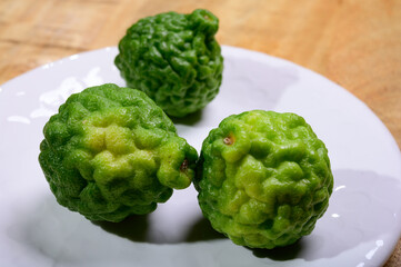 Obraz premium kaffir lime or makrut lime, citrus fruit native to tropical Southeast Asia. Fruit and leaves used in Southeast Asian cuisine, essential oil is used in perfumery for intense citrus fragrance.