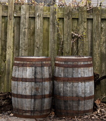 Old wooden barrels outside near wooden fence.