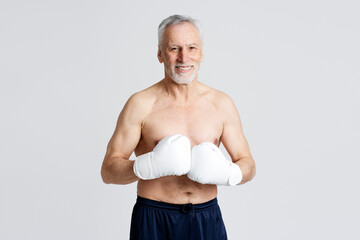 Portrait of attractive senior man wearing boxing gloves training isolated on white background