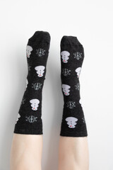 Photo of a pair of women's socks being worn by a caucasian woman. Her feet are posing up against the wall. 