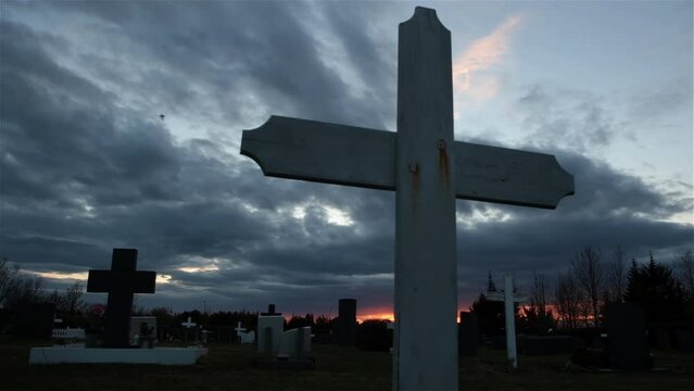 Cemetery cross sliding shot, evil dark cloudy sky red dawn glow