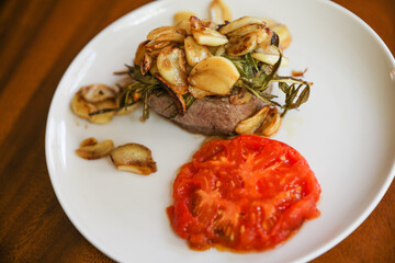 A mouth-watering steak dinner with tomato and garlic represents a balance of indulgence and healthy nourishment. Symbolizing strength, vitality, and a celebration of life