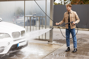 Man cleaning car using high pressure water. Self service concept