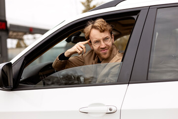 Angry nervous man driving a car, hurry up,  had an accident on the road. Emotional driver stuck in traffic jam, holding index finger on temple. Transportation concept