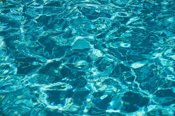 Fototapeta na wymiar Ripple Water in swimming pool with sun reflection. Wavy water background.