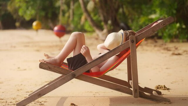 Boy Lying On Sun Lounger With Hat On His Face