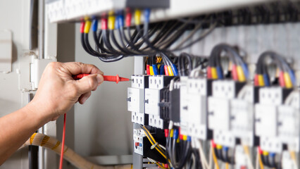 Electrical engineer checking the operation of electrical control cabinet, maintenance concept.	