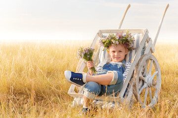 Child plays in a field on a summer day. Little girl with a bouquet of flowers in a garden...