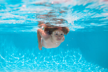 Child swim and dive underwater in the swimming pool. Summer vacation with children.
