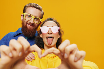 Man and woman couple smiling cheerfully and crooked with glasses, on yellow background, symbols...
