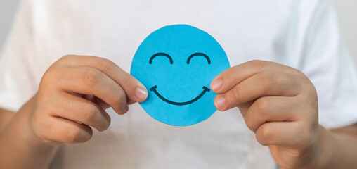 Child hand hold paper cut circle symbol face smile, emotions, happy, relax, satisfaction survey, customer services, positive, good, wellness, health child, hospital, world mental health day concept