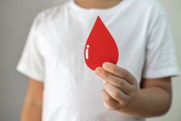 Child kid hand holding blood drop donation, save life, world hemophilia day concept, world blood...