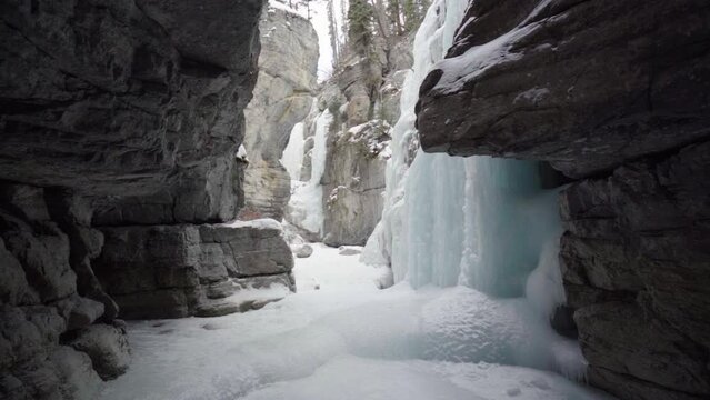 epic view of rozen waterfall inside maligne canyon over frozen river in slow motion