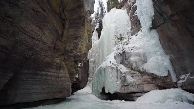 epic view of rozen waterfall inside maligne canyon over frozen river in slow motion