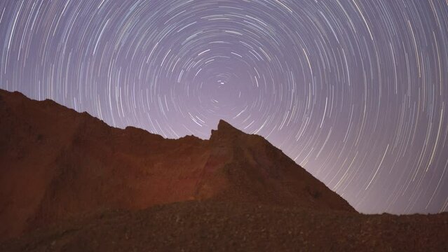 4K Time-Lapse Video motion of night sky with circular star trails over the rock formations mountains foreground. Mae Moh, Lampang, Thailand.
